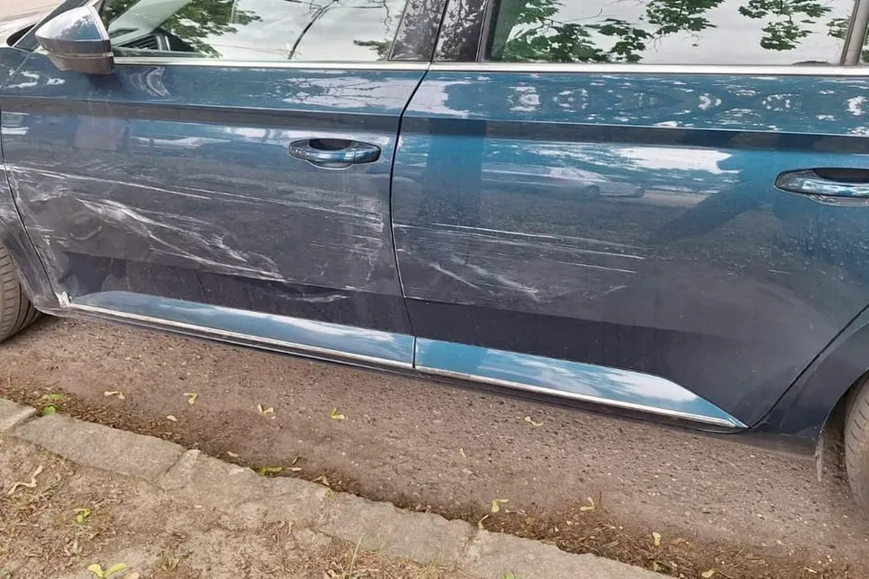 Koccanás nyoma egy Škoda Superb oldalán: végigkarcolt ajtók és küszöb, az utcán fényképezve