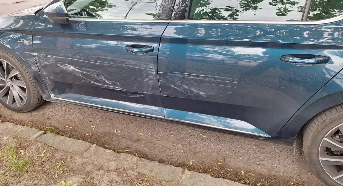 Koccanás nyoma egy Škoda Superb oldalán: végigkarcolt ajtók és küszöb, az utcán fényképezve