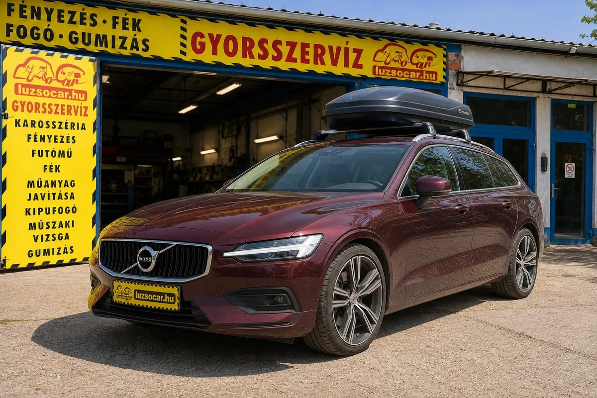 Bordó Volvo kombi tetőboxszal és Luzso Car rendszámtakaróval a műhely előtt